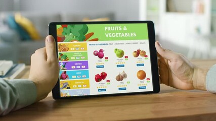 Wall Mural - Person Uses Tablet Computer with Touch Screen, Browsing through Online Food Delivery Market, Choosing Vegetables in Fresh Goods Section. Internet Store with List of Products to Order. POV view