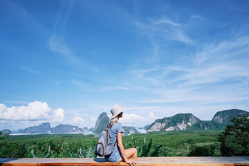 Wall Mural - Traveling by Thailand. Young tourist woman enjoying wonderful view of Phang Nga bay with rock islands.