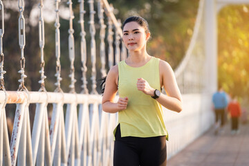 A young Asian woman runner athlete in sports outfit jogging and workout in the city park in the morning. Healthy lifestyle young sporty asian woman running at tropical park. Sport and recreation