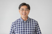 Portrait Close Up Shot Of Middle Aged Asian Male Model With Short Black Hair Wearing Blue Plaid Shirt With Stand Smiling In Front Of White Background