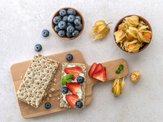 Rye oats crispbread with cottage cheese, mint leaves, fresh strawberries, and blueberries. Top view. Healthy food snack.