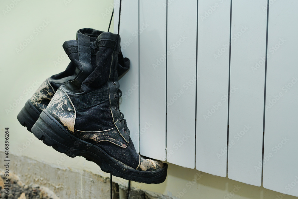 Old dirty ragged builders boots hangs on lace at construction site - obrazy, fototapety, plakaty 