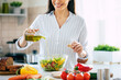 © My Ocean studio - Close up photo of a smiling young woman makes a fresh vegan salad while she uses olive oil for it.