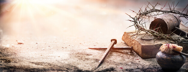 passion of jesus christ - hammer and bloody nails and crown of thorns on arid ground with defocused 