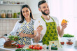 © My Ocean studio - Excited smiling young couple in love making a super healthy vegan salad with many vegetables in the kitchen and having fun