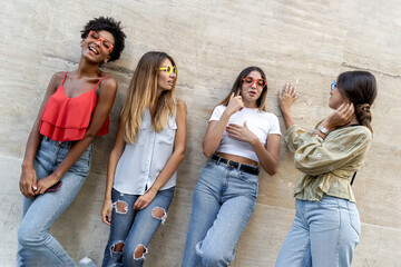 Wall Mural - women only 20s young people chatting together in the street. Urban concept of girls having fun together standing in the city over a concrete wall.