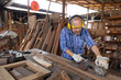 © offsuperphoto - senior asian man carpenter wearing glasses and headphone, using electric wood planers on a piece of wood in workshop