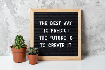 Wall Mural - The best way to predict the future is to create it. Motivational quote on letter board, cactus, succulent flower on white table. Concept inspirational quote of the day. Front view