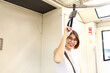 © Nattawat - Asian young short hair beautiful woman wearing glasses holding handle grip while moving in the train
