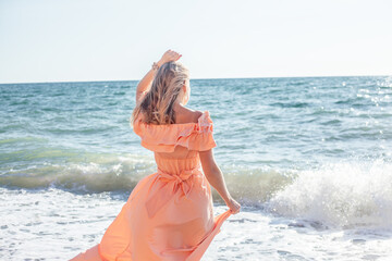 Beautiful woman in maxi dress walking in the beach of the sea