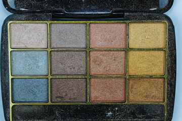 Palette of old eyeshadows. Pearlescent eye shadows in different shades top view. Shiny eyeshadows in a black plastic palette.