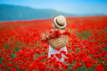 Rear view of a woman in a field with red poppies.