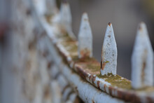 Close Up Of Rusty Historical Fence Topper With Blue Background