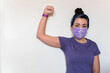 © AliciaFdez - Mujer joven levantando el puño. Lleva una mascarilla desechable con el símbolo de la mujer para protegerse del coronavirus. La chica viste una camiseta morada y un pañuelo. Día de la mujer, 8 Marzo