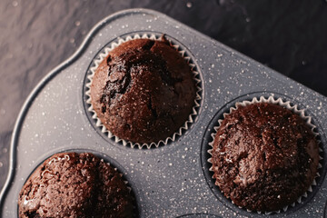 Just baked chocolate muffins in tray, homemade comfort food recipe