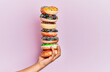 © Krakenimages.com - Hand of hispanic man holding tower of donuts over isolated pink background.