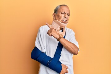 Poster - Handsome mature senior man wearing cervical collar and arm on sling pointing aside worried and nervous with forefinger, concerned and surprised expression