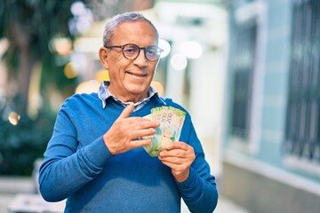 Wall Mural - senior grey-haired man smiling happy counting russian ruble banknotes at the city.