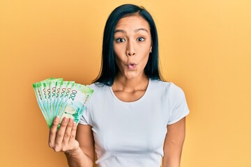 Sticker - Beautiful hispanic woman holding 200 russian ruble banknotes scared and amazed with open mouth for surprise, disbelief face