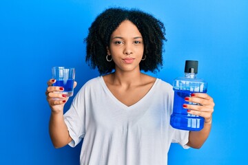 Canvas Print - Young african american girl holding mouthwash for fresh breath skeptic and nervous, frowning upset because of problem. negative person.