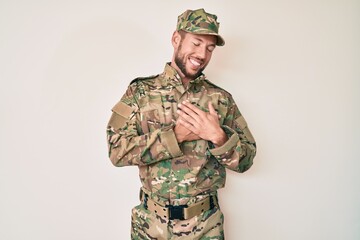 Wall Mural - Young caucasian man wearing camouflage army uniform smiling with hands on chest with closed eyes and grateful gesture on face. health concept.