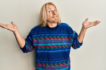 Sticker - Caucasian young man with long hair wearing colorful winter sweater clueless and confused with open arms, no idea and doubtful face.