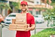 © Krakenimages.com - Young caucasian deliveryman smiling happy holding delivery food at the city.