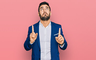 Canvas Print - Young hispanic man wearing business jacket pointing up looking sad and upset, indicating direction with fingers, unhappy and depressed.