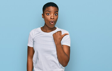 Poster - Young african american woman wearing casual white t shirt surprised pointing with hand finger to the side, open mouth amazed expression.