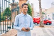 © Krakenimages.com - Young latin man smiling happy using smartphone walking at the city.