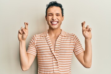 Handsome man wearing make up wearing casual t shirt gesturing finger crossed smiling with hope and eyes closed. luck and superstitious concept.