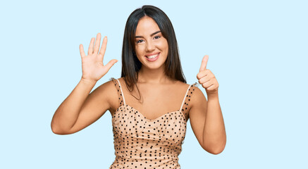 Wall Mural - Young beautiful hispanic girl wearing sexy party dress showing and pointing up with fingers number six while smiling confident and happy.