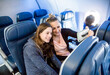 © Brocreative - Two women taking a selfie together while traveling on an airplane. A mother and daughter sitting on an airplane and excited about their upcoming vacation. Smiling happy faces