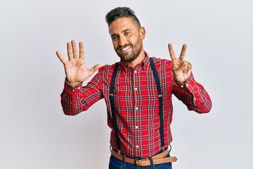 Wall Mural - Handsome man with beard wearing hipster elegant look showing and pointing up with fingers number seven while smiling confident and happy.