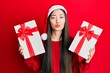 © Krakenimages.com - Young chinese woman wearing christmas hat and holding gifts looking at the camera blowing a kiss being lovely and sexy. love expression.