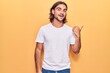 © Krakenimages.com - Young handsome man wearing casual clothes smiling with happy face looking and pointing to the side with thumb up.