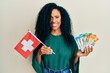 Middle age african american woman holding switzerland flag and franc banknotes smiling with a happy and cool smile on face. showing teeth.