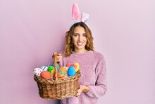 Young Caucasian Woman Wearing Cute Easter Bunny Ears Holding Colored Egg Smiling With A Happy And Cool Smile On Face. Showing Teeth.