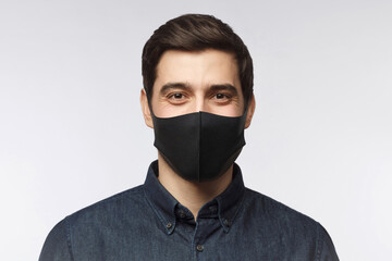 Poster - Young man wearing denim shirt and black mask standing isolated on gray background