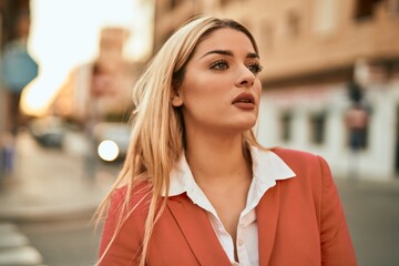 Young blonde businesswoman with serious expresison standing at the city.