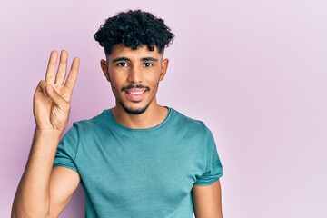 Wall Mural - Young arab handsome man wearing casual clothes showing and pointing up with fingers number three while smiling confident and happy.