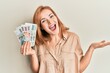 © Krakenimages.com - Young caucasian woman holding czech koruna banknotes celebrating achievement with happy smile and winner expression with raised hand