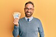 © Krakenimages.com - Handsome middle age man holding swiss franc banknotes looking positive and happy standing and smiling with a confident smile showing teeth