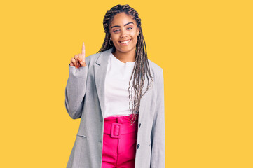 Sticker - Young african american woman with braids wearing business clothes showing and pointing up with finger number one while smiling confident and happy.