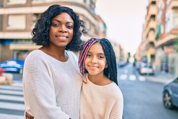 Poster - Beautiful african american mother and daughter smiling happy and hugging. Standing with smile on face standing at the city.