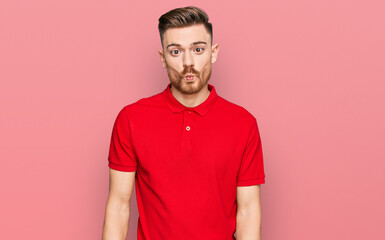 Young redhead man wearing casual clothes making fish face with lips, crazy and comical gesture. funny expression.