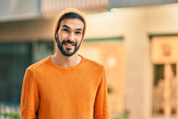 Young hispanic man wearing winter style smiling happy at the city.