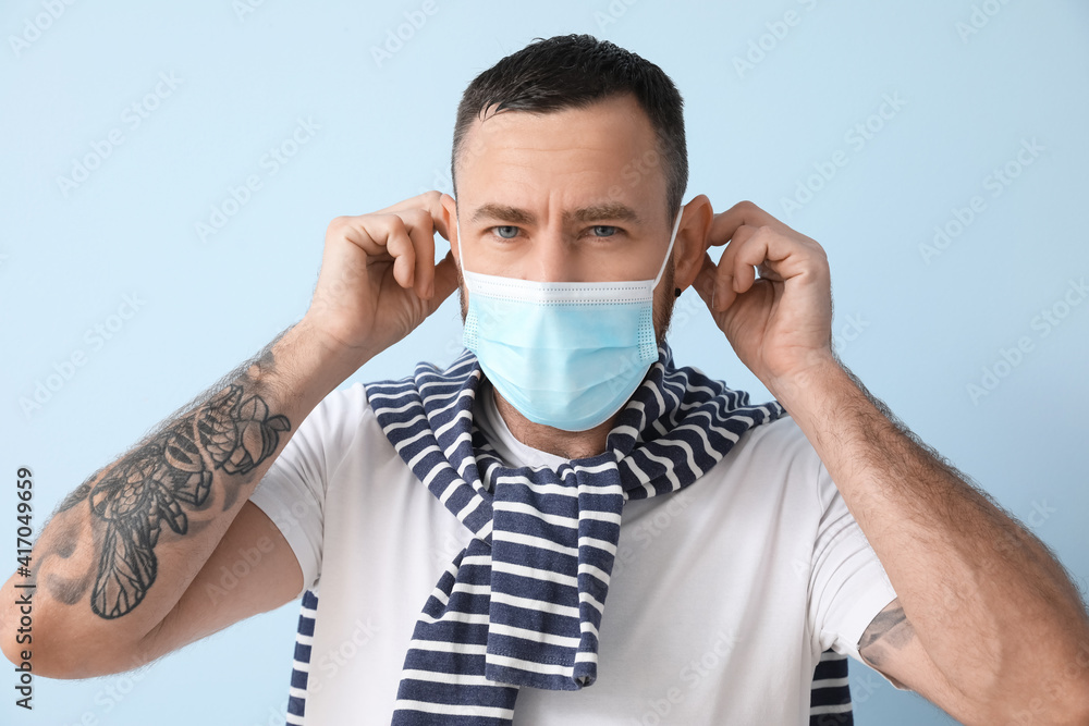 Man wearing medical mask on color background