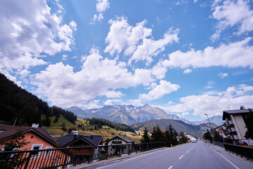 Asphalt road in Alps mountains at hills and mountain village background. Road trip concept.