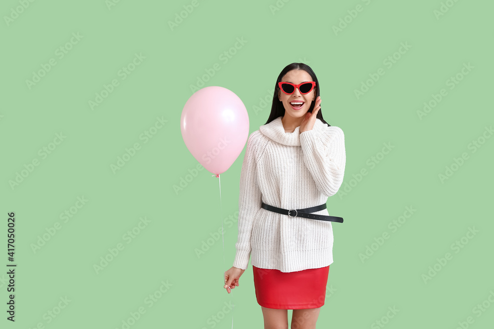 Beautiful young woman with balloon on color background